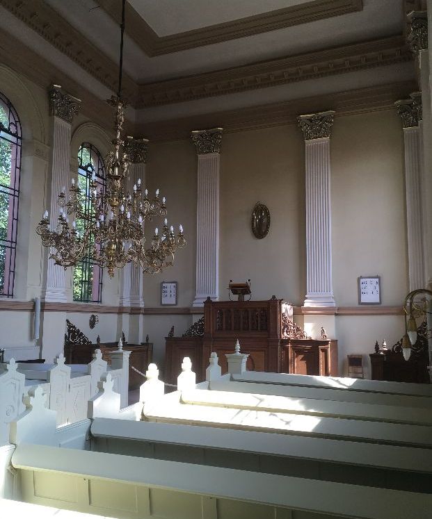 Kircheninnenraum mit Bänken und Kronleuchter.