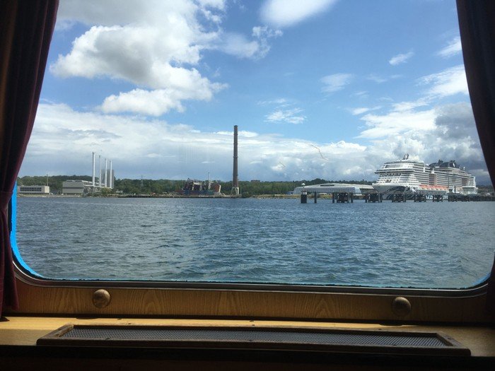 Kreuzfahrtschiff und Industrielandschaft vom Boot aus.