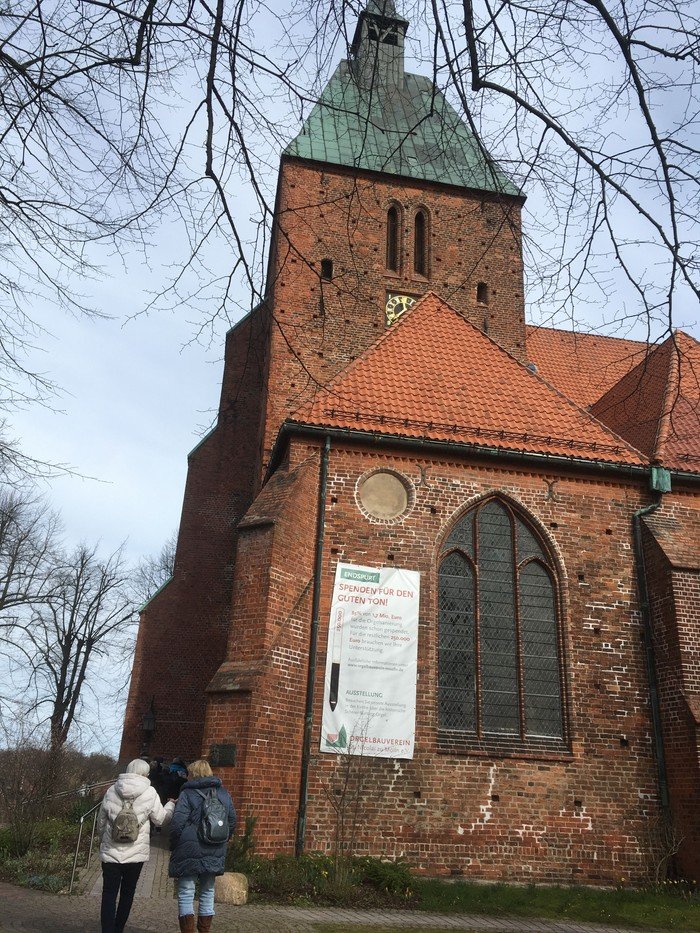 Zwei Personen gehen auf eine Backsteinkirche zu.
