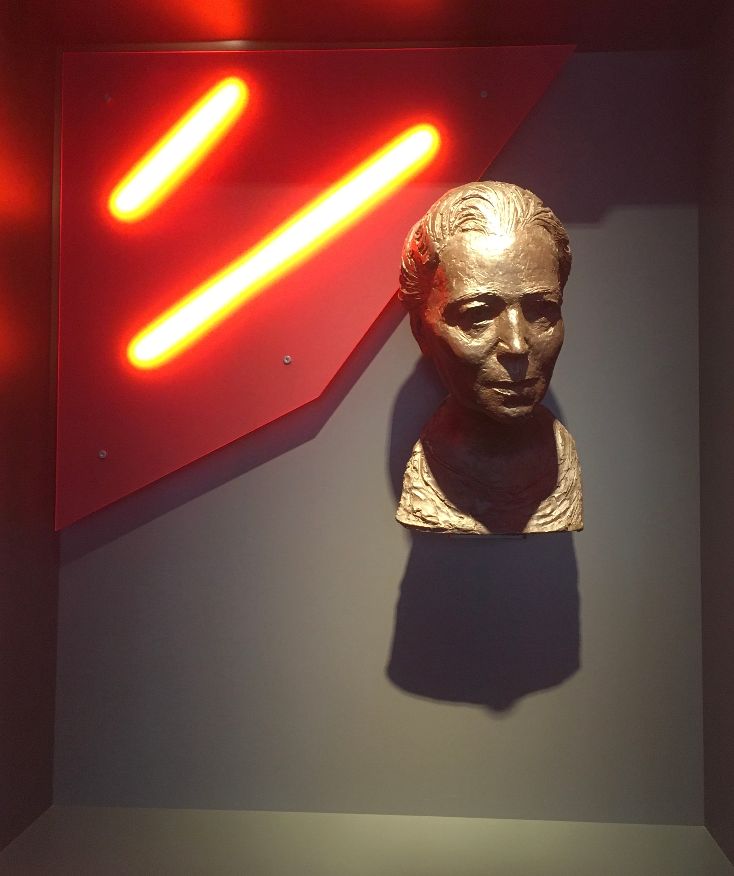 Büste mit Neonlichtern im Hintergrund.