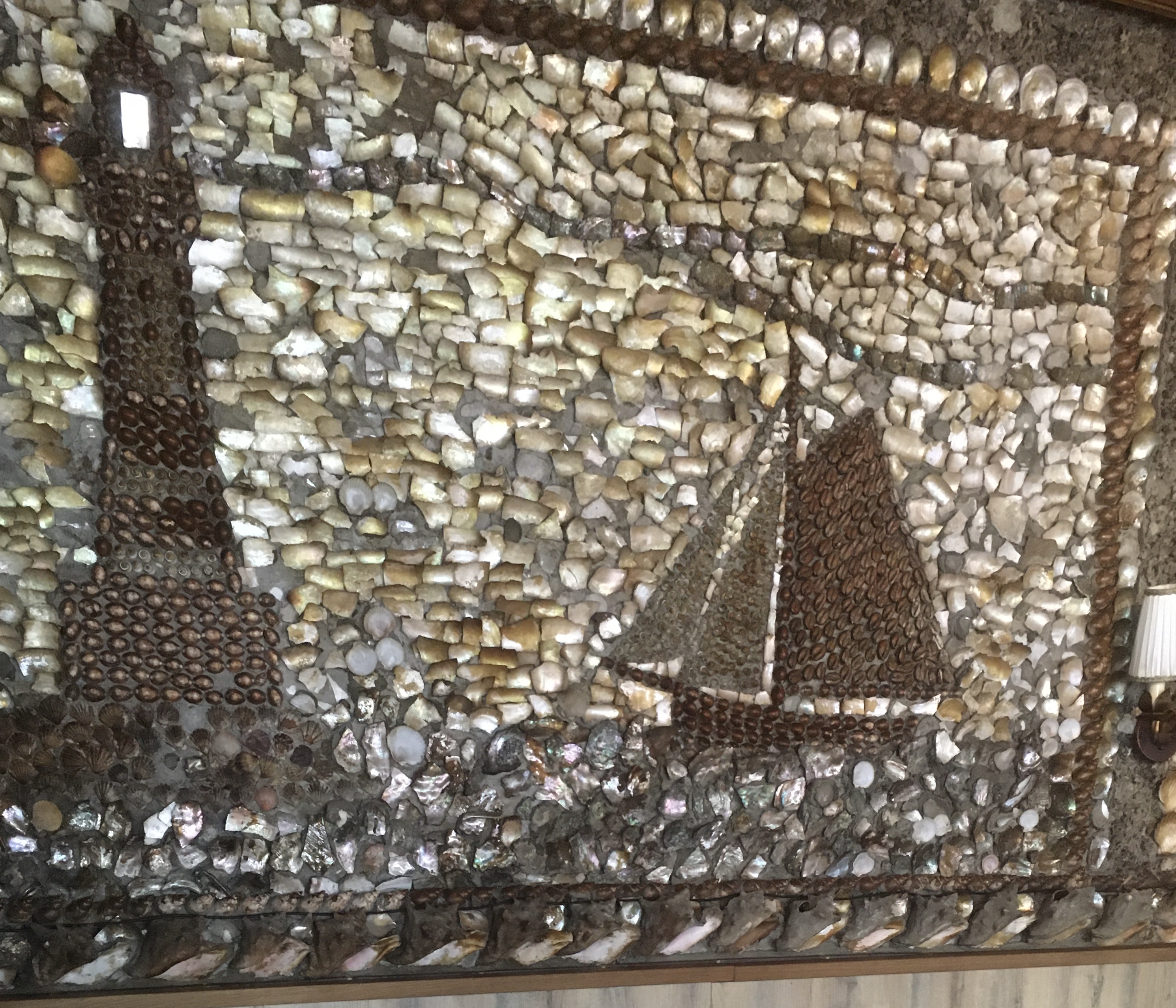 Wandkunst aus Muscheln mit Segelboot.