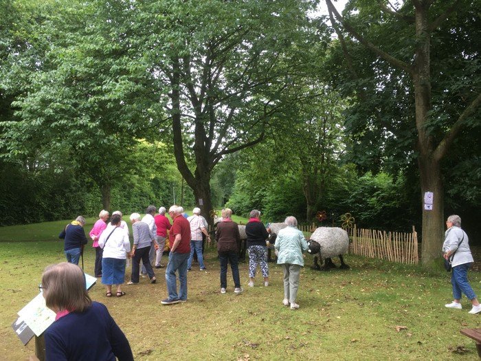 Menschen betrachten Schaffiguren im Park.