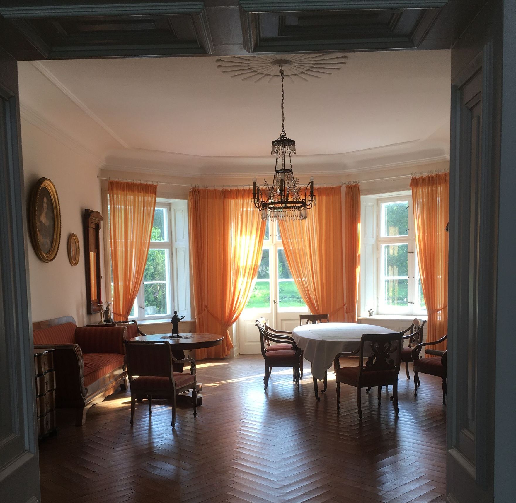 Elegantes Zimmer mit Kronleuchter und großen Fenstern.