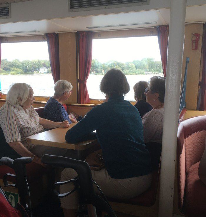 Menschen sitzen an Tischen auf einem Boot.