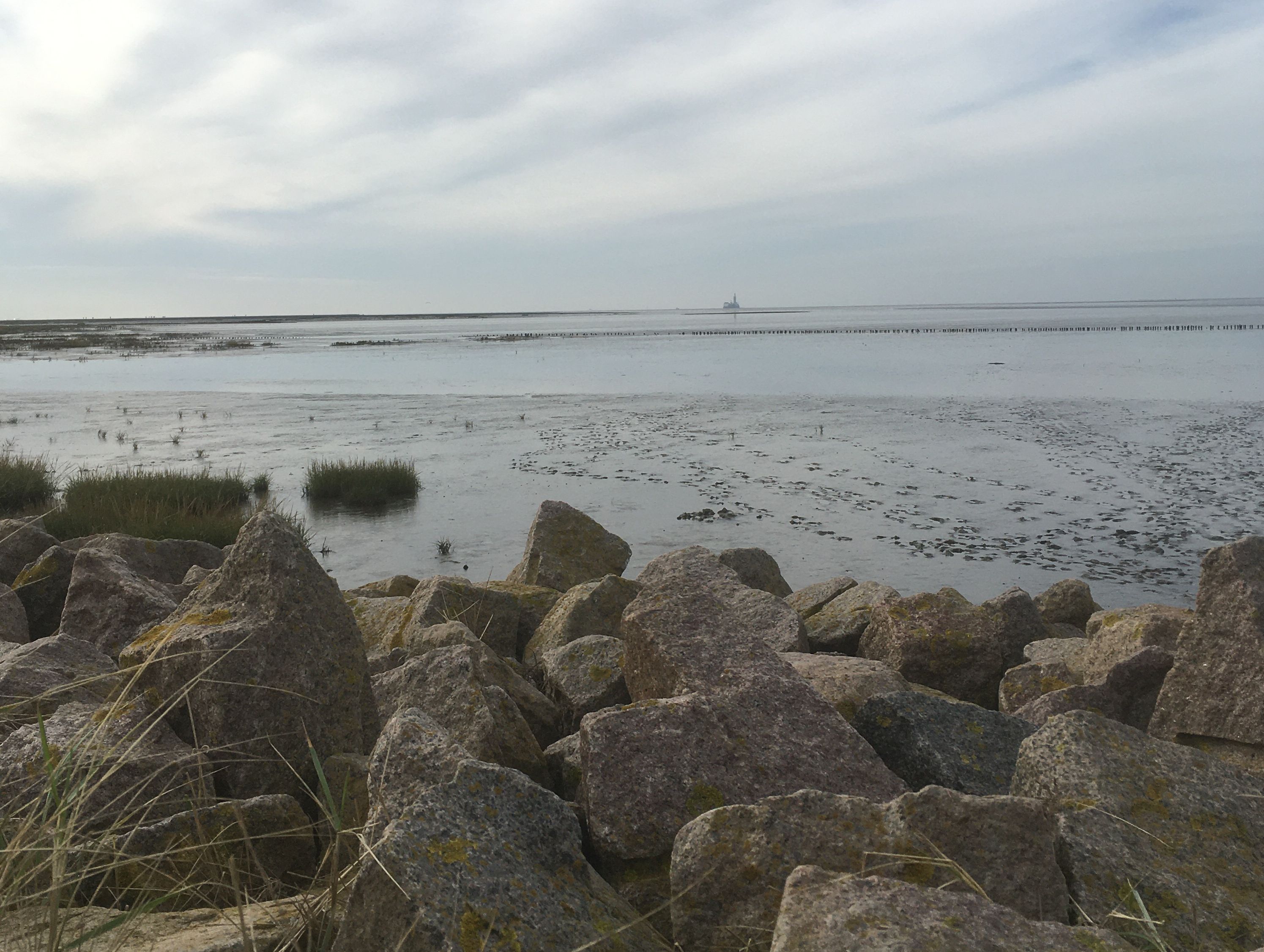 Felsen und Wasser am Strand unter Wolken.