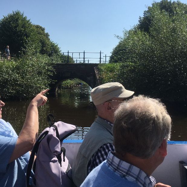 Menschen auf einem Boot zeigen auf eine Brücke.