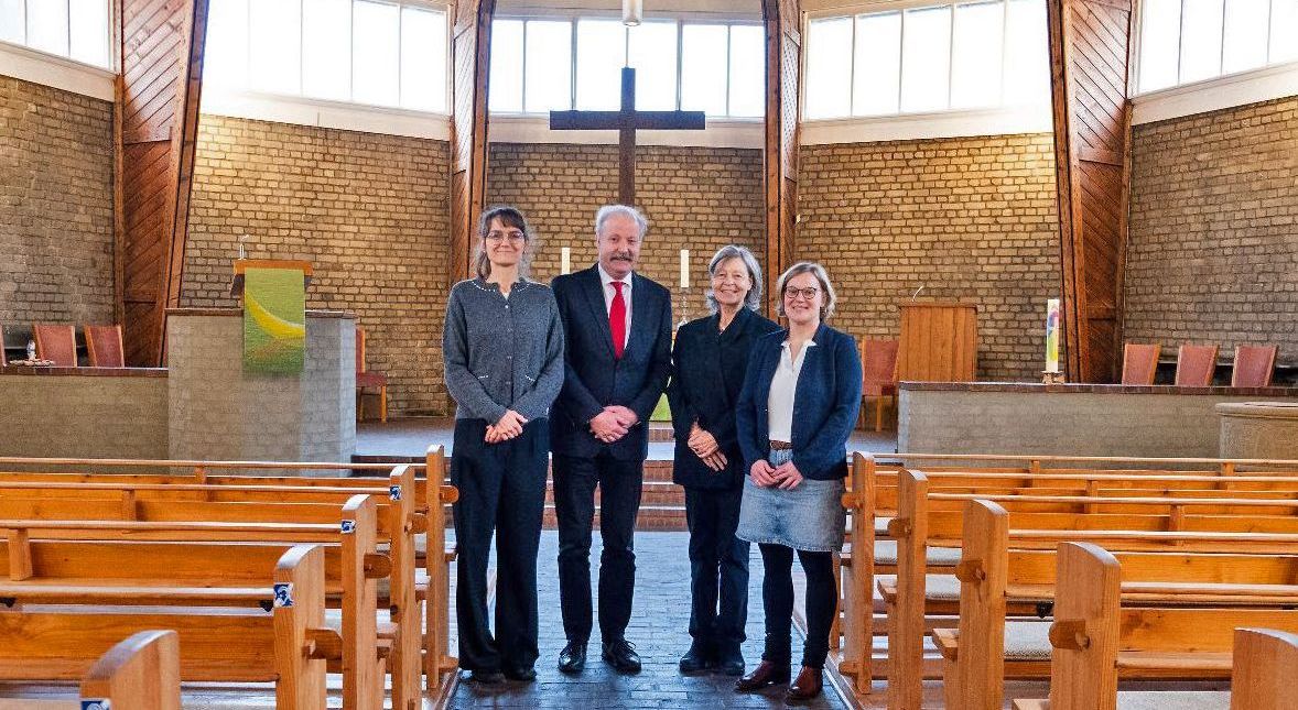 Vier Personen stehen in einer Kirche.