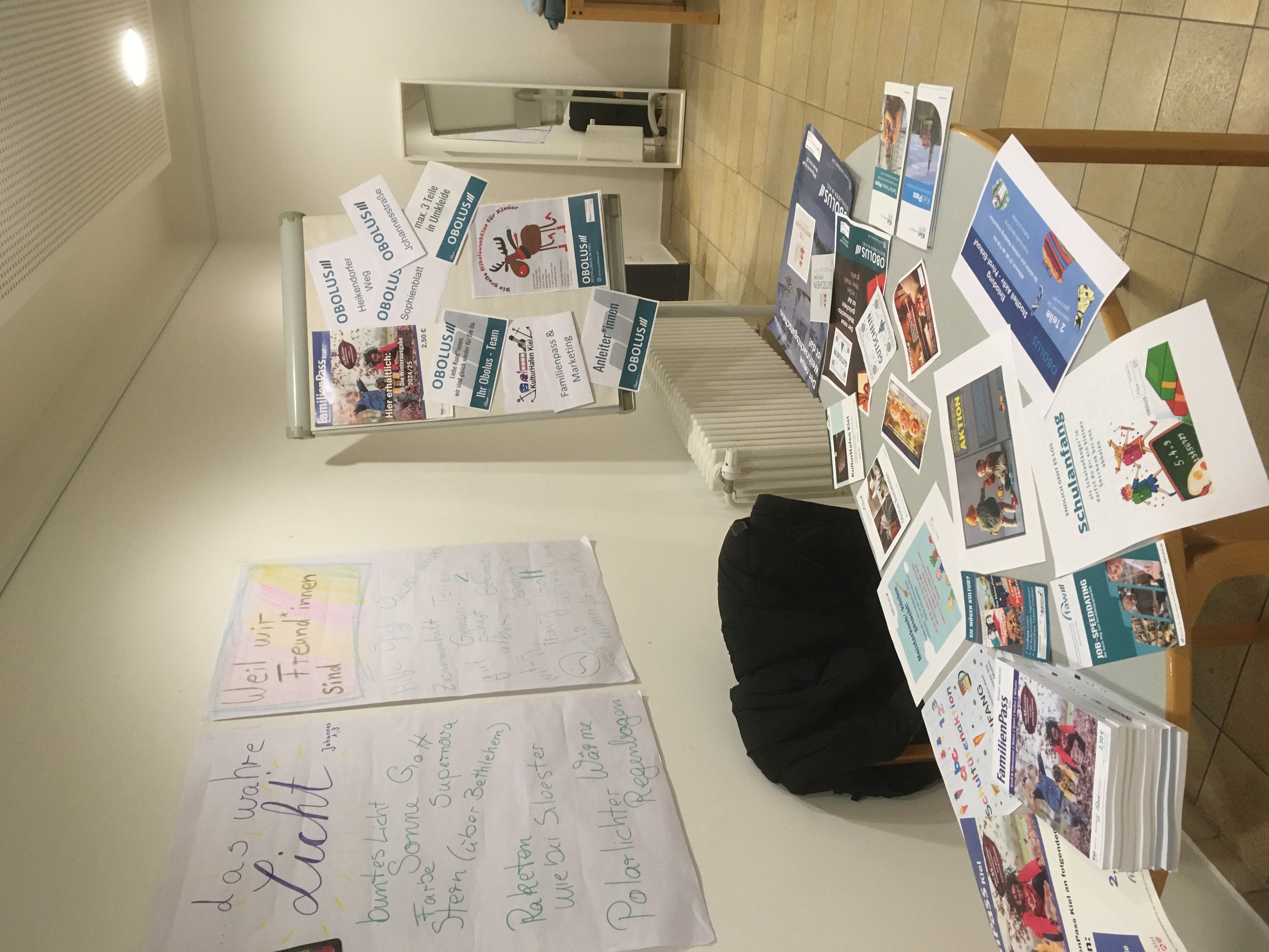 Tisch mit Flyern und Plakaten für Veranstaltungen.