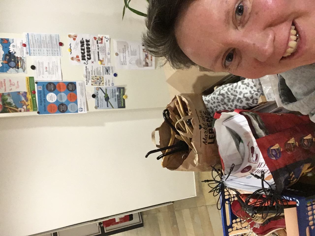 Lächelnde Person mit Einkaufstrolley und Taschen.