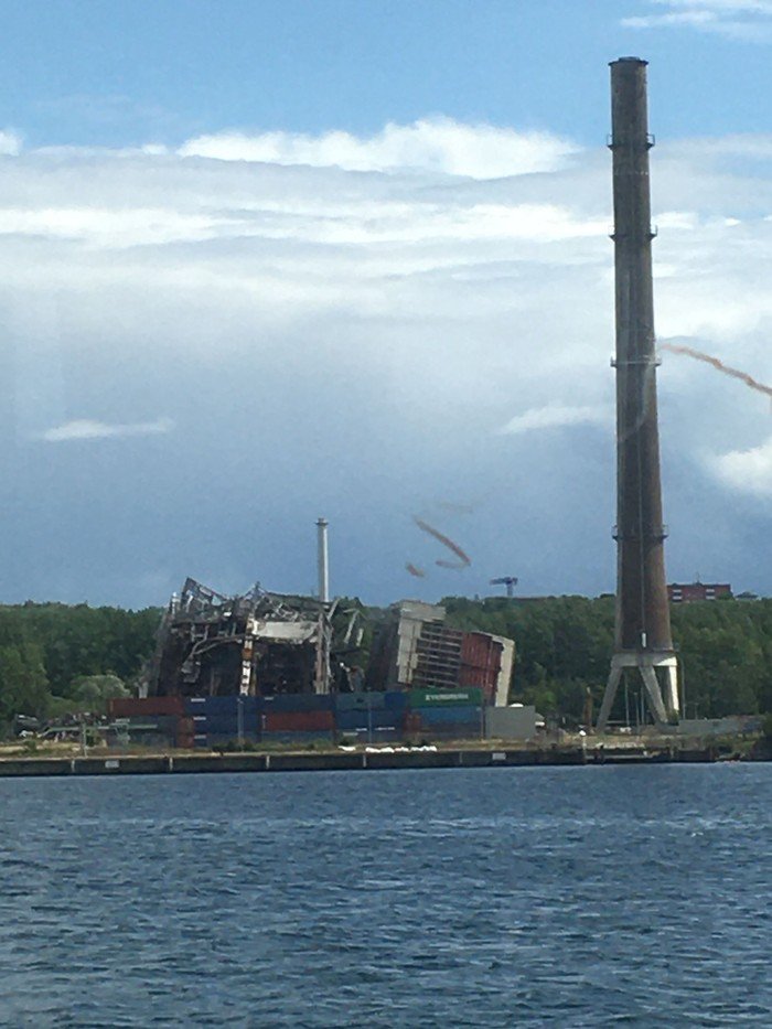 Industriekomplex mit hohem Schornstein und Wasser.