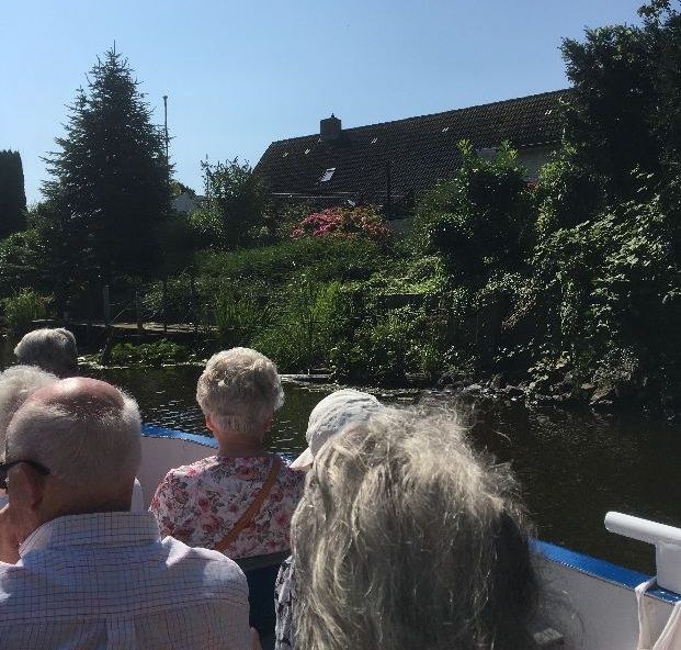 Bootsfahrer blicken auf Häuser und Natur.
